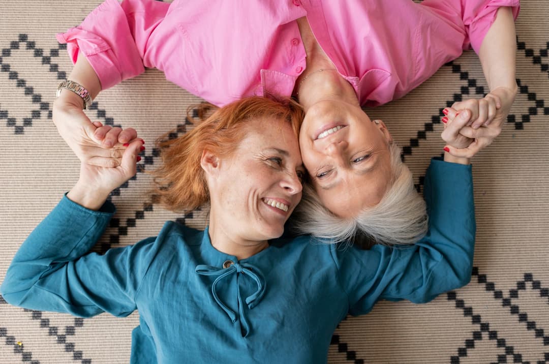 Two,Mature,Women,Lying,Upside,Down,On,Carpet,Looking,At